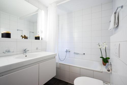 a bathroom with a sink and a toilet and a tub at Chesa Murmina No. 1 in Zuoz