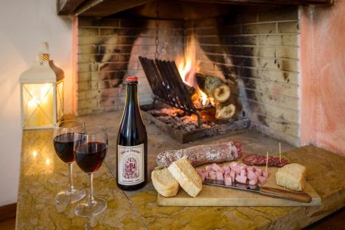 a bottle of wine next to two glasses of wine and a fireplace at Agriturismo Querceto in Frazione Mocaiana