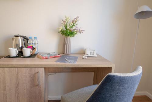 a desk with a vase of flowers and a telephone at Taverna de la Sal Boutique Hotel in L'Escala