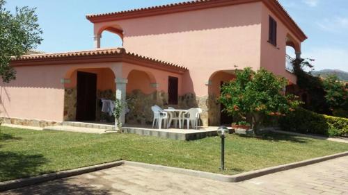 a pink house with a table and chairs in a yard at Sardegnadream in San Teodoro