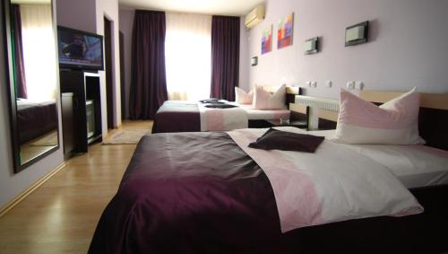 a hotel room with two beds and a television at Hotel Poarta Transilvaniei in Bistriţa