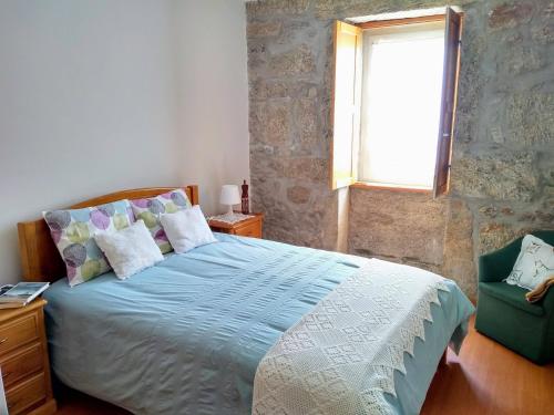a bedroom with a bed and a window and a chair at Casa do Pinheiro Manso in Valença