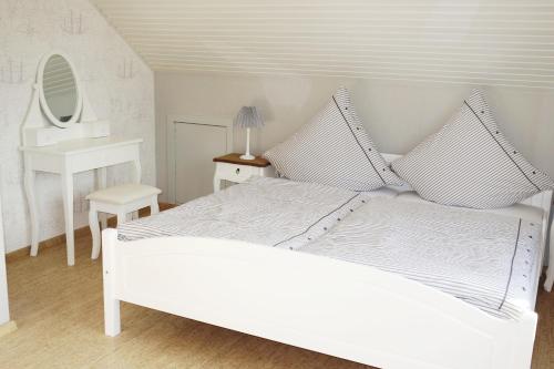 a white bedroom with a white bed and a mirror at Ostseezauber in Pelzerhaken