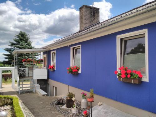 a blue house with flower boxes on the windows at Haus der 16 Seen in Krakow am See