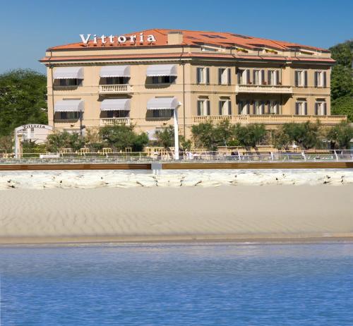 a building on the beach next to the water at Hotel Vittoria in Pesaro