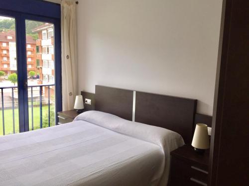 a bedroom with a bed and a large window at La Barquera in Ribadesella