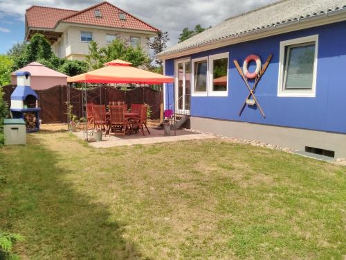 a blue house with a table and an umbrella at Haus der 16 Seen in Krakow am See