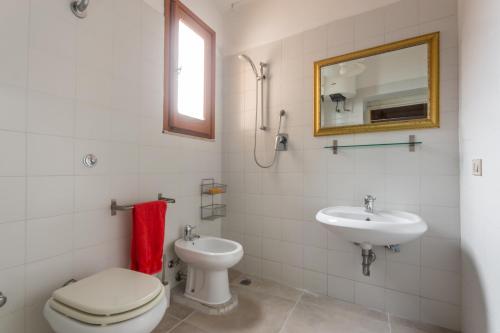 uma casa de banho com um WC, um lavatório e um espelho. em Casa Bea Bosa/Magomadas em Magomadas