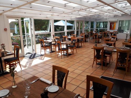 un restaurante con mesas y sillas de madera y ventanas en Møn Golf Resort - Hotel Præstekilde, en Stege