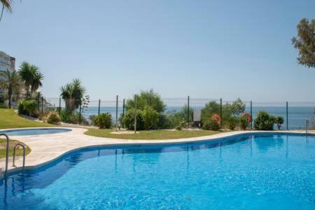 a large blue swimming pool with the ocean in the background at Relax Frente al Mar in Benalmádena