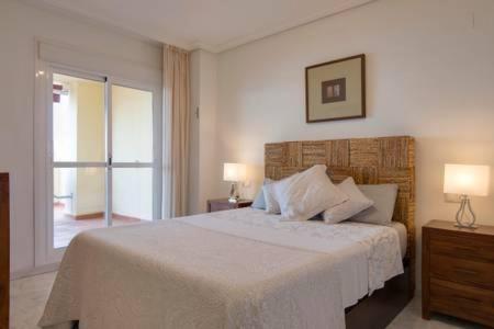 1 dormitorio con 1 cama blanca grande y 2 lámparas en Relax Frente al Mar, en Benalmádena