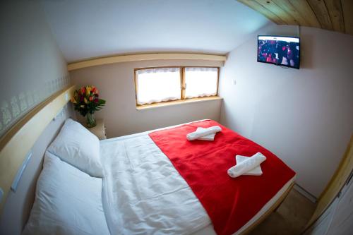 a small room with a bed with a red and white blanket at GLUTEN FREE Bed & Breakfast Dežela Okusov in Ljubljana