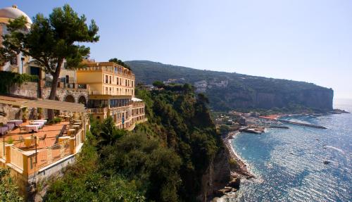 a group of buildings on a cliff next to the ocean at Hotel Sporting in Vico Equense