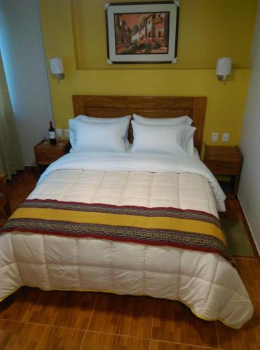 a large white bed in a bedroom with yellow walls at Picos House MachuPicchu in Machu Picchu