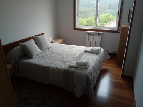 1 dormitorio con 1 cama con 2 toallas en Apartamento Cefas en O Pedrouzo