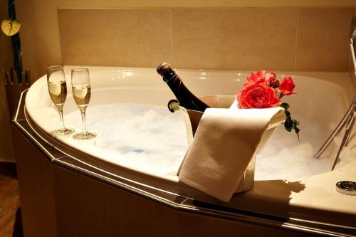 una bottiglia di champagne in una vasca da bagno con 2 bicchieri da vino di Christiana's Wein & Art Hotel a Bernkastel-Kues