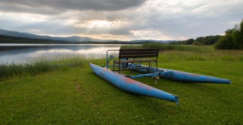 a bench and two canoes on the grass next to a lake at Camping u Kukačků in Horní Planá