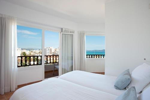a white bedroom with a view of the ocean at Galaxia Boutique Hotel in Can Picafort