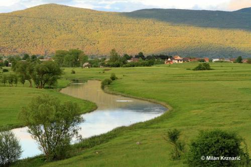 a river in a field with a mountain in the background at Apartman Karlo in Otočac