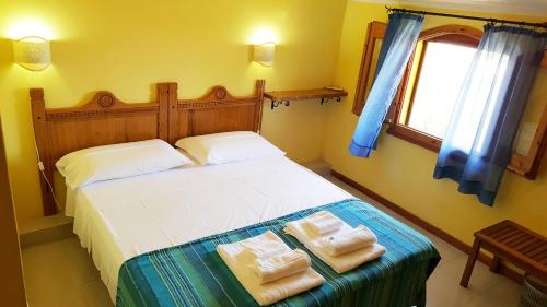 ein Schlafzimmer mit einem Bett mit zwei Handtüchern darauf in der Unterkunft La Baia Apartments in Putzu Idu
