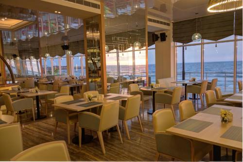 a restaurant with tables and chairs and the ocean at Lancaster Eden Bay in Beirut
