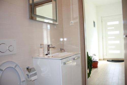 a white bathroom with a sink and a toilet at Apartment Stipe in Maslenica