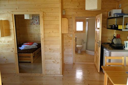 a wooden cabin with a bed and a toilet at LIDO - domy letniskowe z klimatyzacją in Krynica Morska