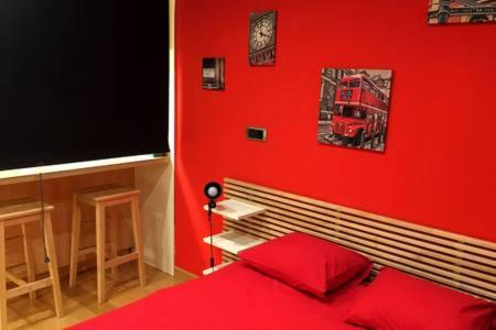 a red room with a bed and a red wall at ESTUDIO MODERNO CENTRO-PLAYA GIJÓN in Gijón