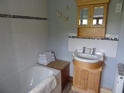 y baño con bañera, lavamanos y bañera. en Swallow Cottage en Oakworth