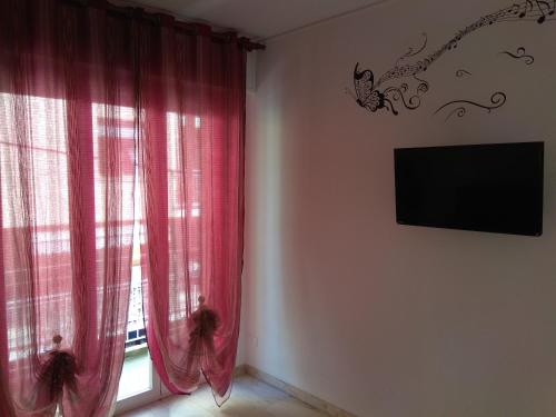 a room with a window with red curtains and a tv at Da Cipollina in Pieno Centro in Sanremo