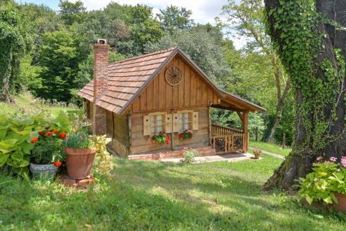 a small log cabin in a yard with flowers at Grebengradska Medna Hiža in Donje Makojišće