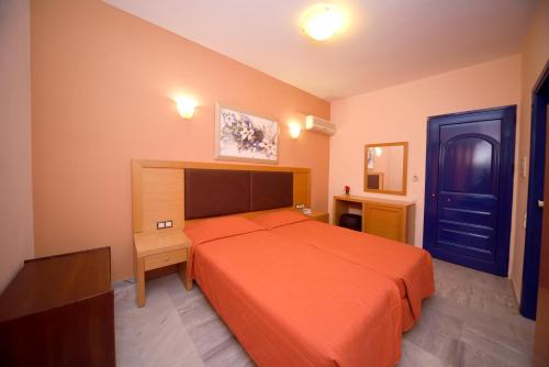 1 dormitorio con cama naranja y puerta azul en Hotel Palazzo, en Archangelos