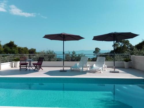 a patio with chairs and umbrellas next to a swimming pool at Villa Filip in Makarska