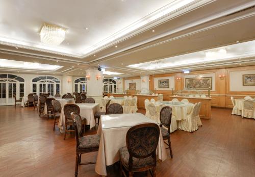 a dining room with tables and chairs with white table cloth at Forbes Hotel in Taichung