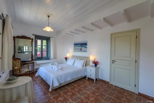 a bedroom with a white bed and a table and window at KK Houses in Hydra