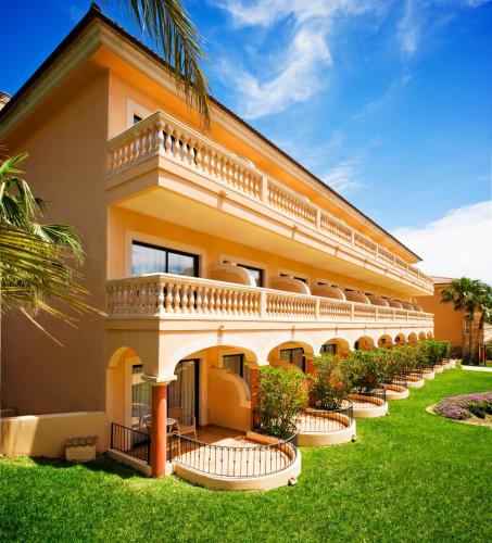 an orange building with a balcony and green grass at Mon Port Hotel & Spa in Port d’Andratx