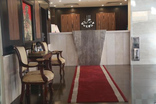 a lobby with a table and chairs and a red rug at Velvet Inn Jeddah in Jeddah