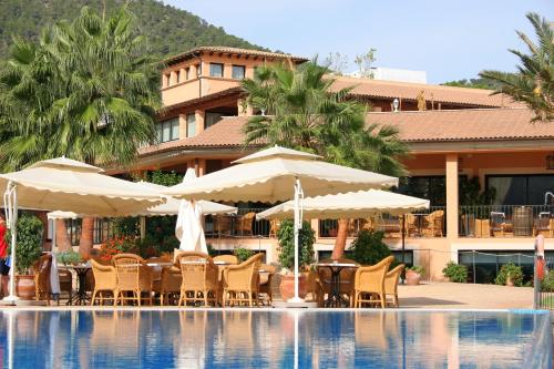 a hotel with chairs and umbrellas next to a swimming pool at Mon Port Hotel & Spa in Port d’Andratx
