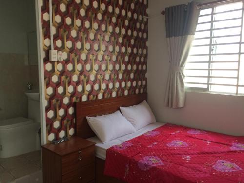 a bedroom with a red bed with a red comforter at BangBang Motel in Can Tho