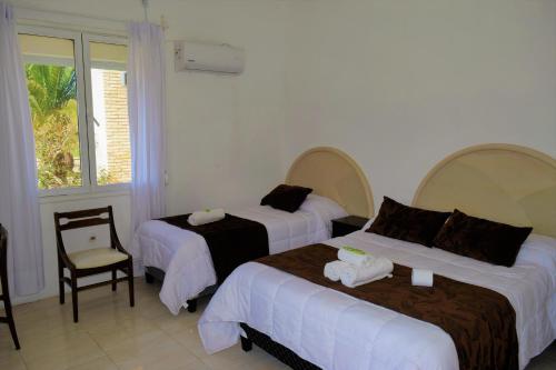 a hotel room with two beds and a chair at Hotel Cabo Santa Maria in La Paloma