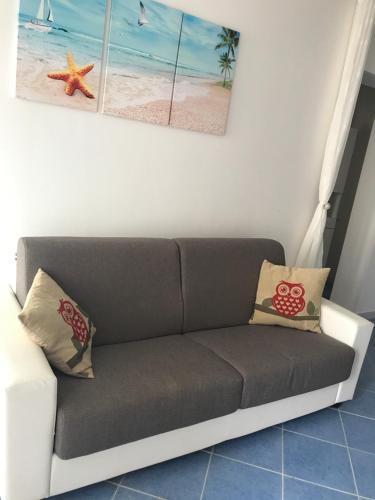 a couch in a living room with paintings on the wall at Villa Azzurra in Marina di Pescoluse