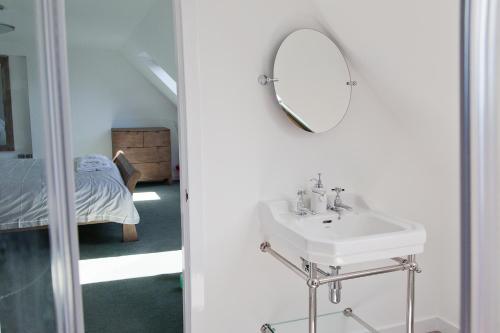 Baño blanco con lavabo y espejo en Belforte House Holiday Home, en Inverness