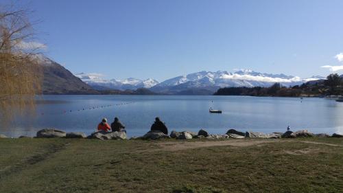 a group of people sitting on rocks near a body of water at Zula Lodge in Wanaka