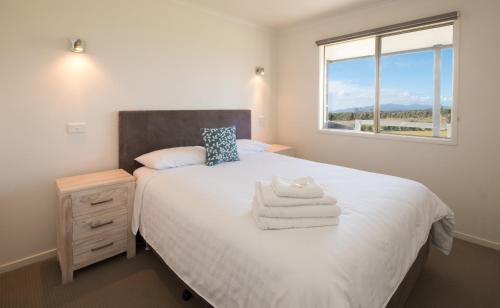 1 dormitorio con 1 cama con sábanas blancas y ventana en Prom Gate Getaway, en Yanakie