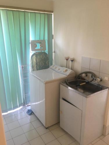 a small room with a washing machine and a sink at Relaxed Ocean View in Mandurah