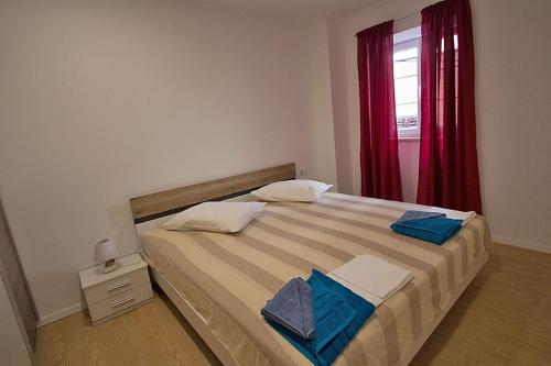 a bedroom with a large bed with a red window at Apartment Carlitos in Karlobag