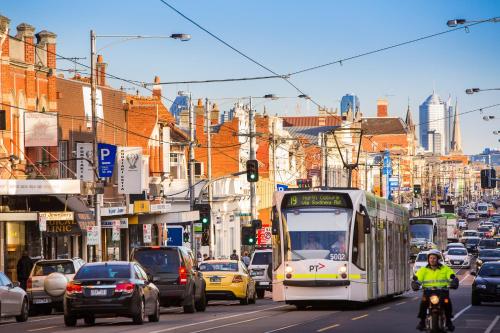 a bus driving down a busy city street with traffic at Parkville Place Serviced Apartments in Melbourne