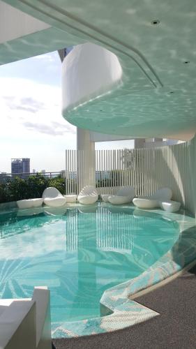 een groot zwembad met witte stoelen in een gebouw bij Modern Luxury Lower Penthouse Unit in Manilla