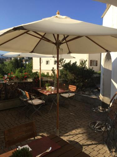 an umbrella on a patio with a table and chairs at Arena Lodge in Flims