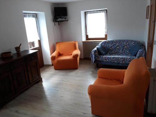 ein Wohnzimmer mit zwei orangenen Stühlen und einem Bett in der Unterkunft Al Becalen in Livinallongo del Col di Lana